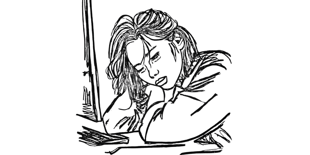 Exhausted woman sitting at desk after overworking — you don’t need to be productive to deserve rest.