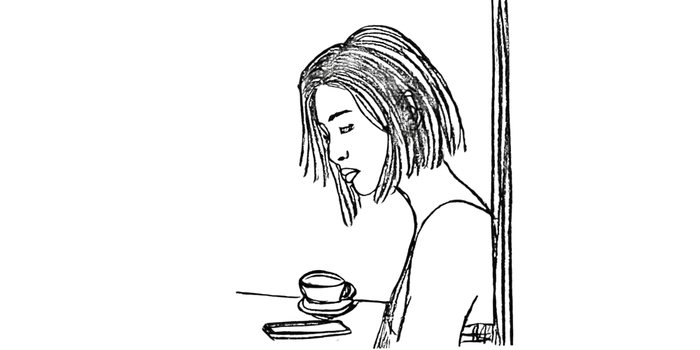 Woman sitting at a table, reflecting quietly with presence